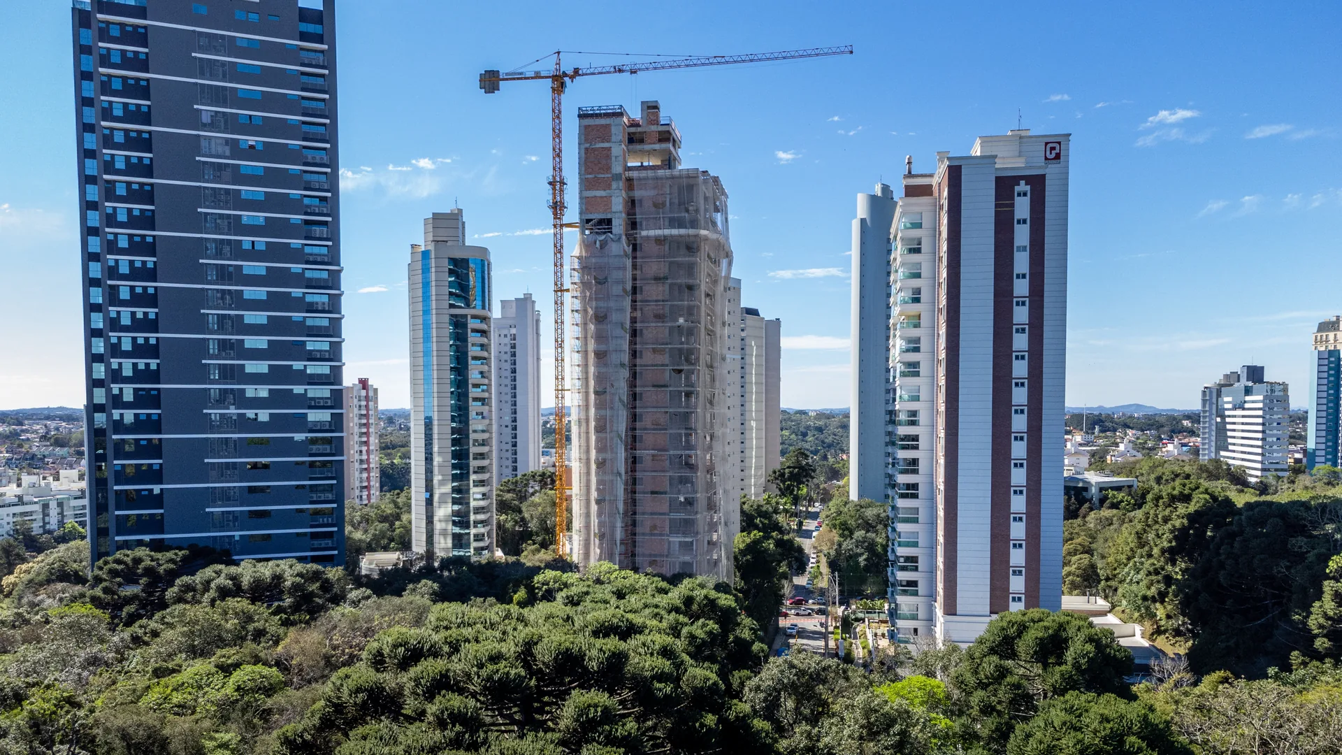 Torres residenciais em construção entre araucárias em Curitiba